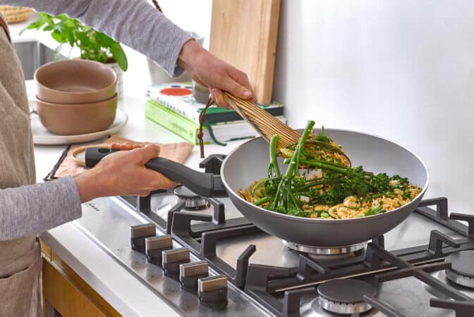 Man holding a stir-fry pan and stirring